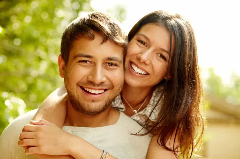 A man and a woman are embracing each other, smiling at the camera.