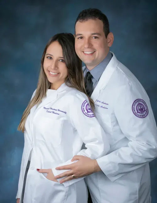 A man and a woman in lab coats, smiling at the camera, posing together for a photo.