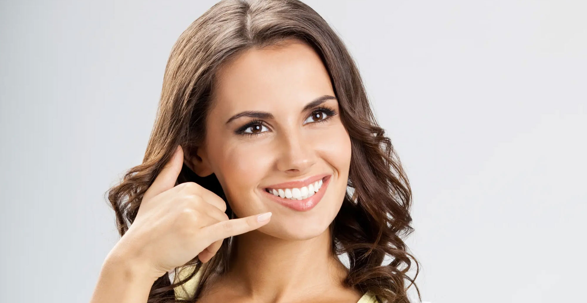 The image shows a woman smiling and holding a phone to her ear, with a clear and focused expression.