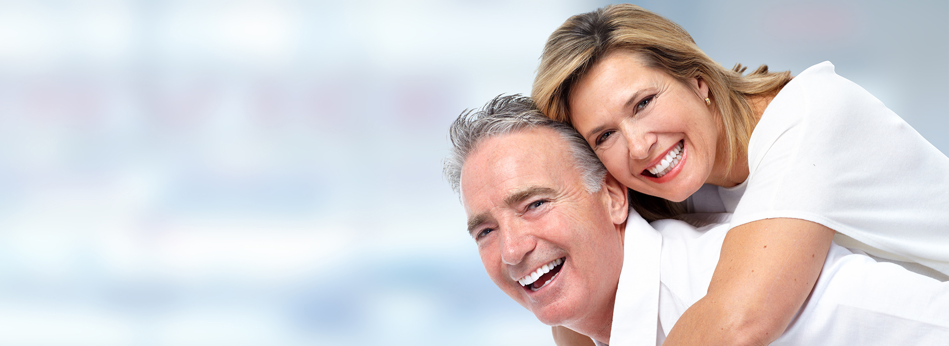 The image depicts a smiling older couple embracing each other, with the man in a white shirt and the woman in a light-colored top.