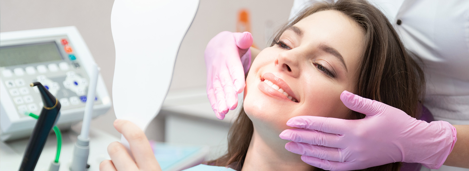 A woman in a dental chair receiving treatment, with a dentist wearing gloves and using a dental drill.