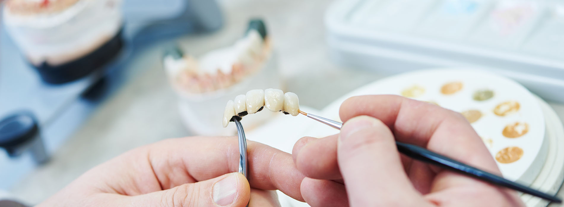 The image shows a person s hands holding tweezers with what appears to be a small piece of food, possibly in the process of decorating or preparing it.