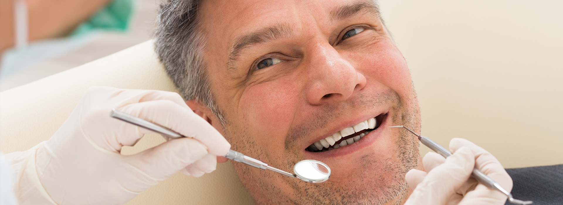 A man in a dental chair, receiving dental treatment with a smile on his face.