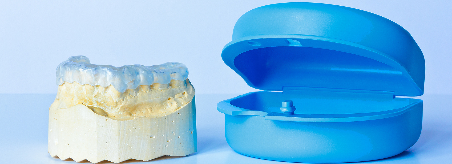 This is a composite image featuring two distinct objects  on the left, there s a transparent plastic dental impression tray, and on the right, there s a blue silicone dental impression material.