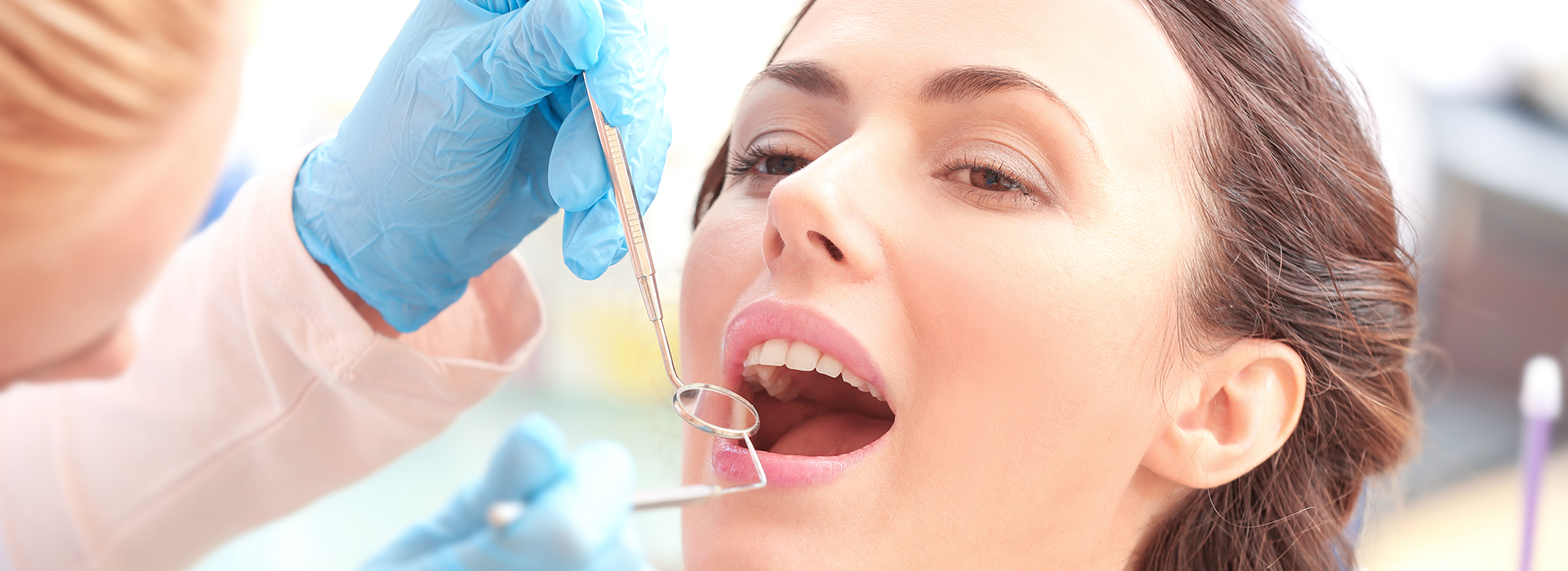 A dental hygienist performing a teeth cleaning procedure on a patient in an office setting.